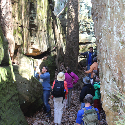 group hiking between two rock formations